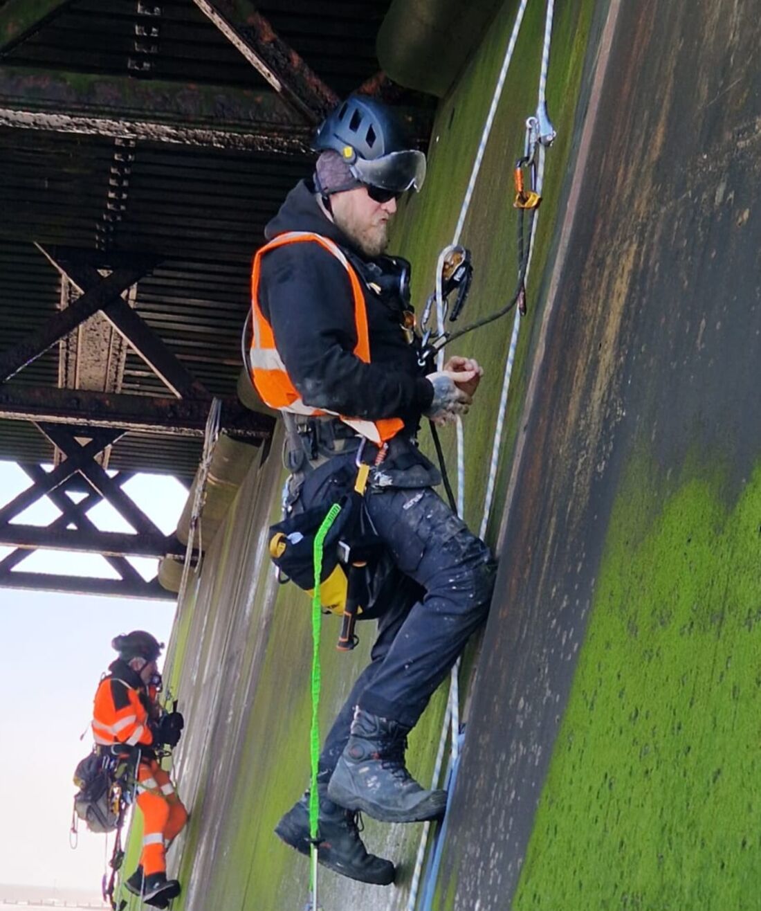 Two rope access technicians inspecting the underside of a steel bridge