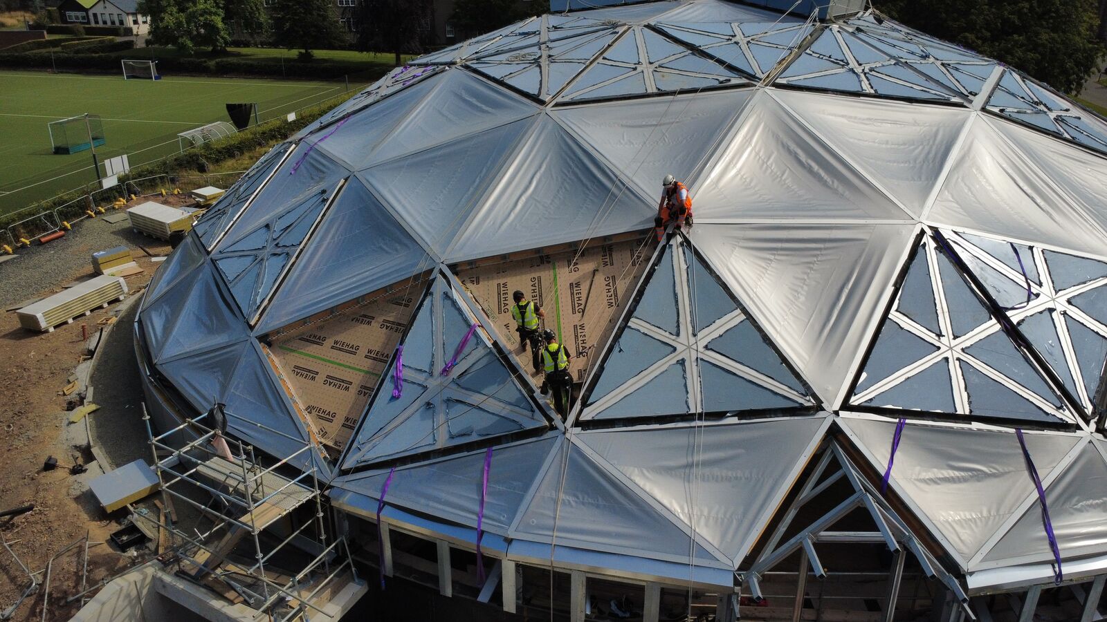 Technicians working on rope on the ETFE panels of a dome roof
